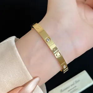Elegant gold stainless steel bangle with zircon stones and heart patterns shown on a wrist