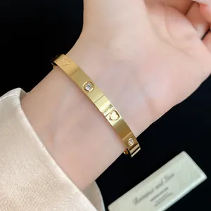 Detail view of a gold stainless steel heart bangle with zircon accents on a wrist