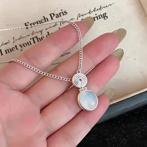 Ethnic silver necklace featuring an oval iridescent resin pendant held in hand display