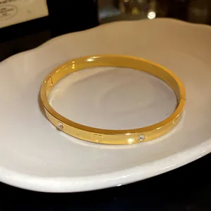Macro detail showing heart engraving and inlaid zircons on a gold stainless steel bangle