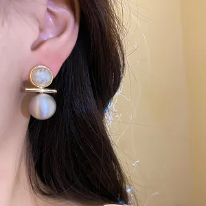 Elegant close-up shot of 18k gold plated brushed pearl stud earrings worn on a model ear