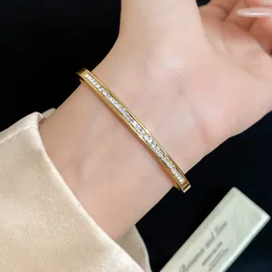 Macro view of an elegant gold stainless steel bangle with a row of clear cubic zircons