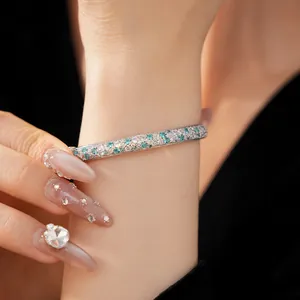 Close-up detail of silver bangle encrusted with white and teal cubic zirconia stones
