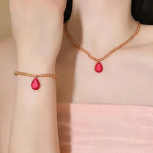 Gros plan détaillé d'un ensemble de bijoux en perles avec pendentifs goutte rouge