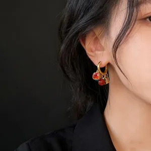 Close-up detail shot of 18k gold plated earrings with zircon and cat's eye stone charms.