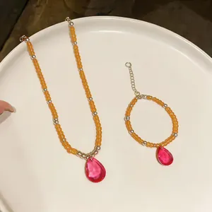 Vue détaillée de l'ensemble collier et bracelet en perles avec pendentifs gouttes roses.