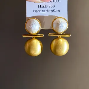 Close-up of 18k gold plated brushed ball earrings with elegant pearls