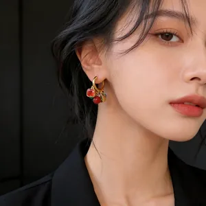 Close-up of 18k gold-plated hoop earrings with vibrant zircon and cat's eye stone charms.