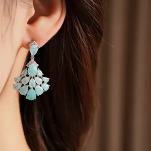 Elegant teardrop fan-shaped tassel earrings with shimmering blue stones shown on ear