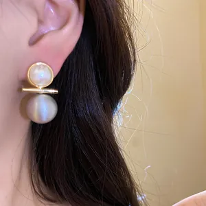 Detail view of 18k gold plated pearl stud earrings with a minimalist bar design on an ear