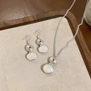 Vintage silver resin oval pendant necklace and earring jewelry set on a neutral linen tray.