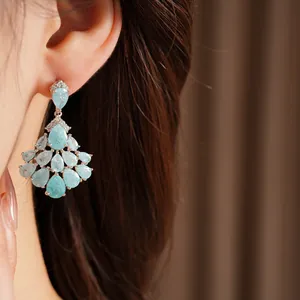 Close-up of 14k gold plated fan-shaped earrings with blue teardrop stones.