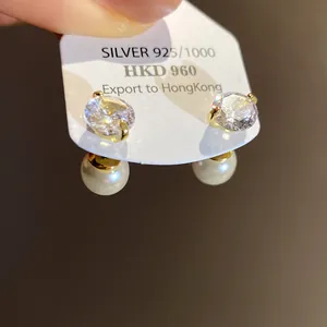 Detailed macro view of gold-finish pearl and cubic zirconia earrings on display.
