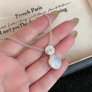 Close-up macro view of a silver ethnic resin oval pendant necklace with spiral design