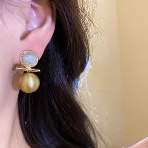 Close-up detail of 18k gold-plated earrings featuring brushed metal ball and pearlescent inlay