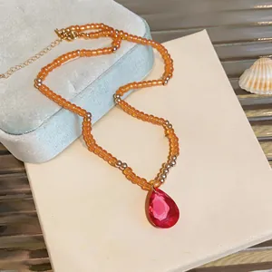 Vue détaillée du collier de perles orange avec pendentif cristal goutte rouge