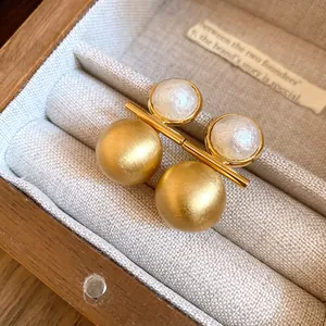 Detailed view of 18k gold plated brushed earrings with elegant white pearl accents