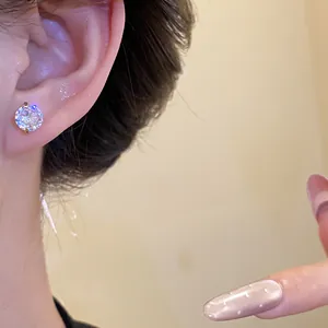 Detail of a classic round zirconia stud earring with a gold setting worn on the ear