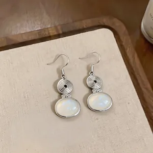 Detail view of ethnic style silver ear hook earrings with elegant oval resin pendants