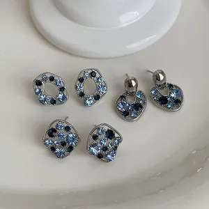 Vista dettagliata di un set di orecchini a lobo geometrici con strass blu e argento