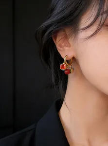 Close-up of vintage 18k gold plated hoop earrings featuring colorful red zircon charms