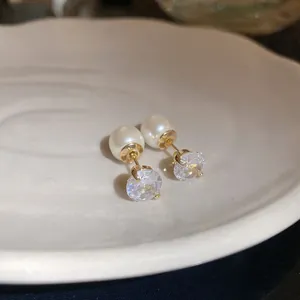 Close-up detail of gold-tone front-and-back earrings with pearl and clear zircon