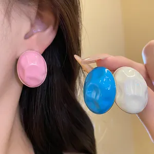 Detailed view of colorful wrinkled enamel oval stud earrings worn on a model's ear