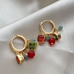 Close-up of luxury 18k gold plated hoop earrings with colorful zircon charms on satin