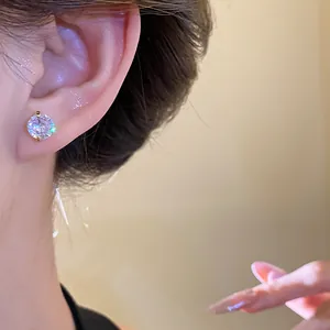Close-up view of a sparkling round zircon stud earring in a gold-colored claw setting