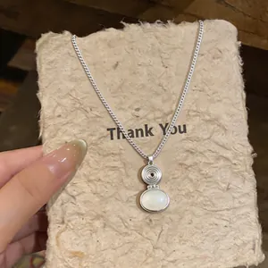 Detail showing ethnic style resin oval pendant and silver chain on textured paper