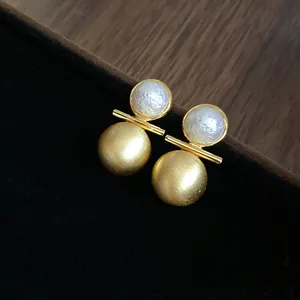 Detail of 18k gold-plated stud earrings with pearl and brushed metal sphere