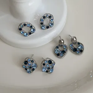 Vista macro di orecchini a lobo geometrici con strass blu in forme eleganti a cuore e cerchio