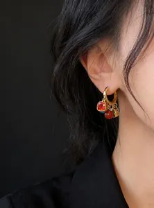 Detail of a woman wearing retro 18k gold plated hoop earrings with multi-colored charms.