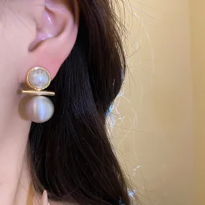 Detailed view of 18k gold plated brushed pearl stud earrings worn on a model's ear