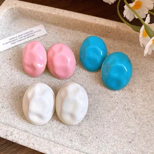 Detailed view of wrinkled texture oval enamel earrings in pink, blue, and white tones.