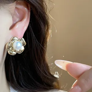 Close-up of 13k gold-plated flower pearl stud earrings worn on ear, French vintage style.