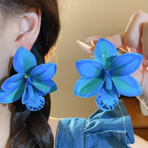 Detailaufnahme der großen, leuchtend blauen Orchideen-Ohrringe mit Drip-Glue-Finish