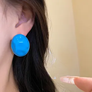 Detail of bright blue oil-dripping oval stud earring with wrinkled texture