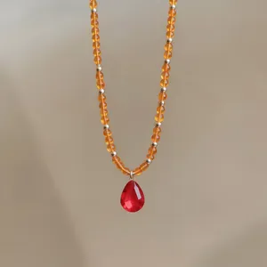 Vue détaillée d'un collier de perles avec un pendentif en cristal rouge en forme de goutte