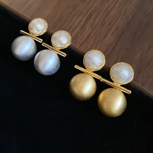 Detailed macro view of elegant 18k gold plated brushed metal and pearl stud earrings