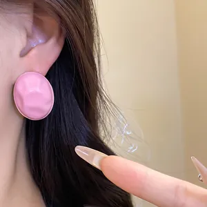 Macro view of minimalist pink crinkle oval drip oil stud earrings worn on female ear.