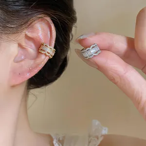 Detailed view of sparkling zircon C-shaped ear cuffs in gold and silver finish.