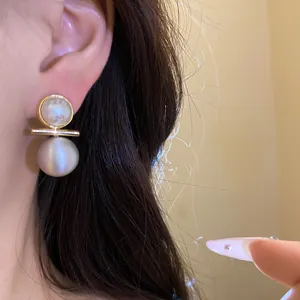Detail close-up of elegant 18k gold plated brushed pearl stud earrings worn on model's ear