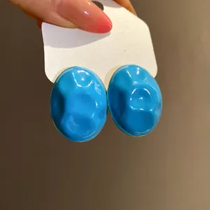 Detailed close-up view of vibrant blue wrinkled enamel oval stud earrings with gloss