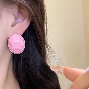 Detailed macro view of pink crumpled elliptical oil-drop stud earring worn on ear