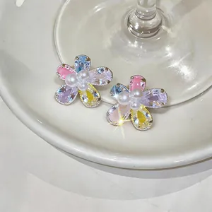Detailed close-up of colorful floral zircon stud earrings with central pearl accents.