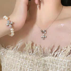 Close-up of elegant rhinestone cross necklace and pearl bracelet set worn by model