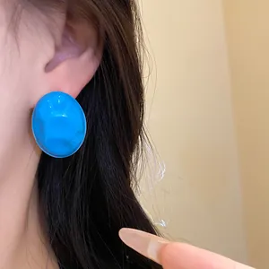 Close-up view of bright blue wrinkled oval drip oil stud earring showing fine textures