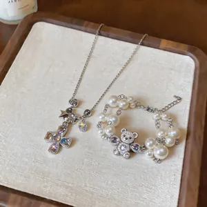 Close-up of silver cross necklace and sparkling bear pearl bracelet in a wooden tray
