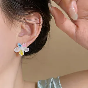 Close-up detail of sweet colorful flower stud earring featuring delicate pearls on ear